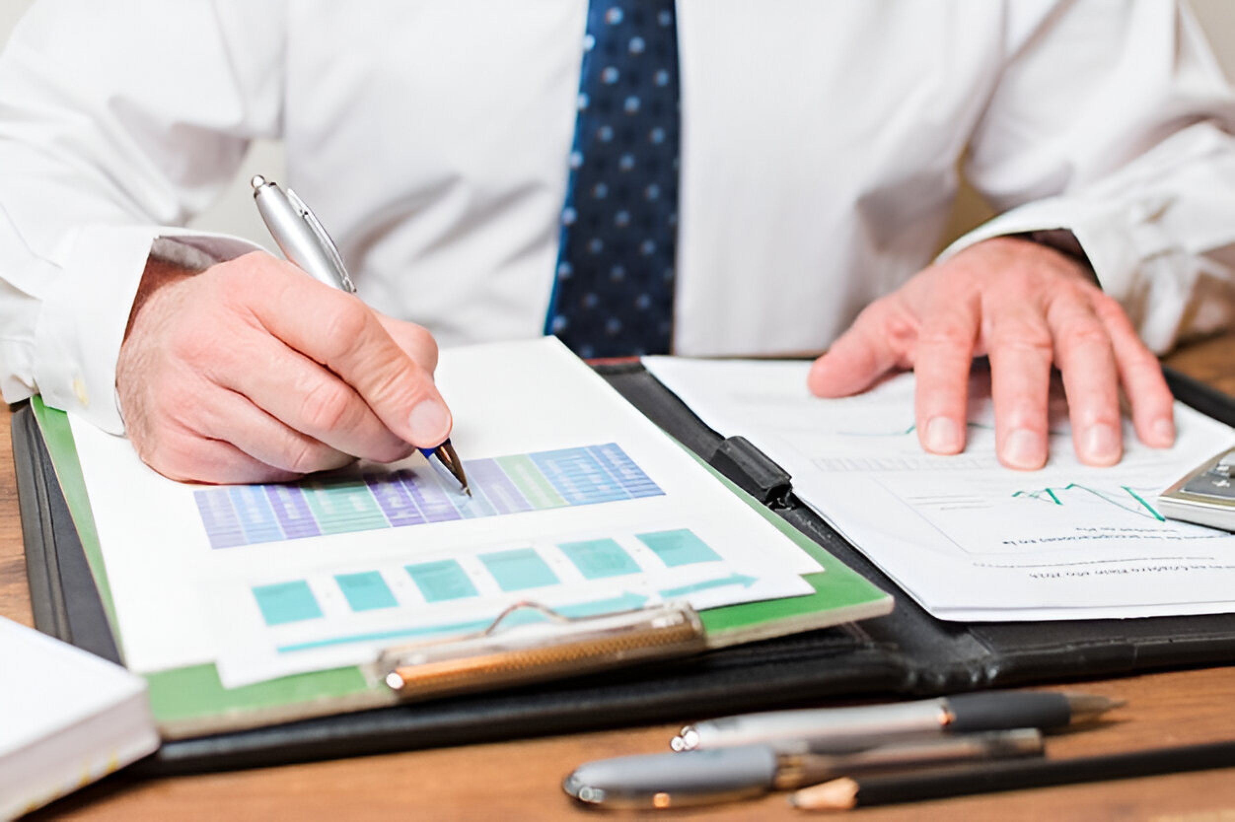 Businessman analyzing financial charts on clipboard.