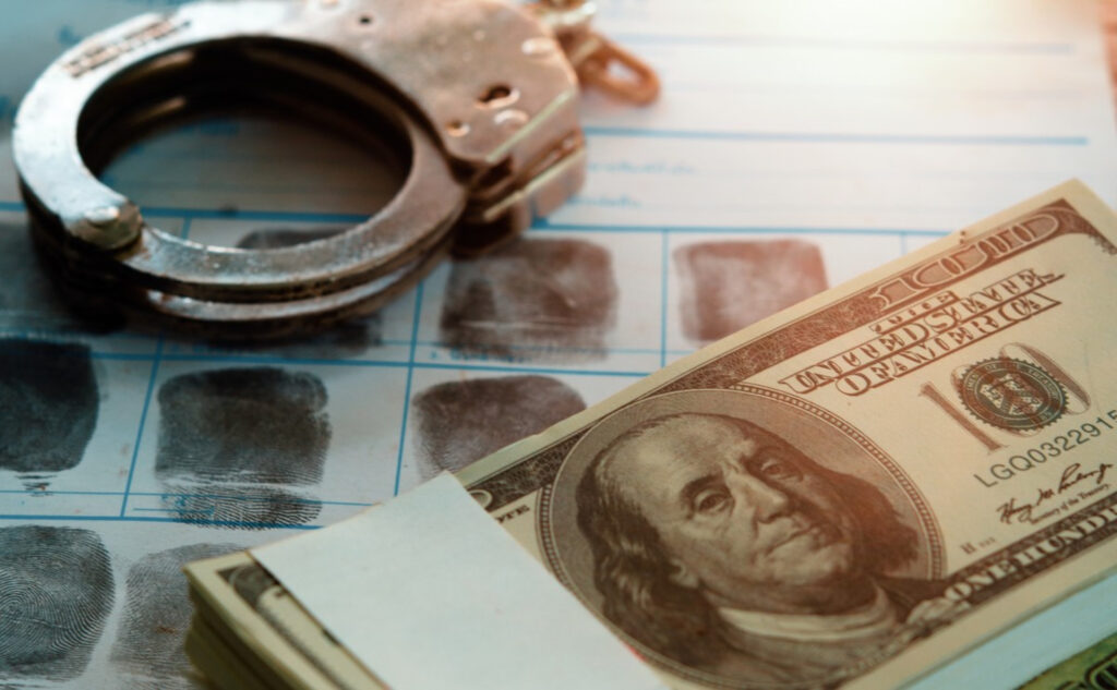 Handcuffs, fingerprints, and cash symbolizing financial crime.