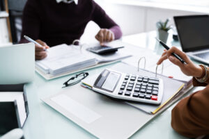 People working on financial documents with calculator.